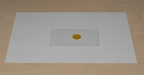 Cleaned lens on lens paper, ready to inspect for streaks