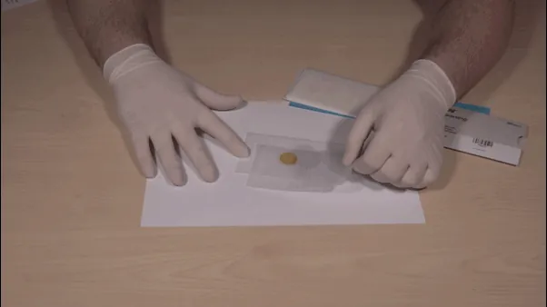 Drawing the wet lens paper slowly across the lens without pressure
